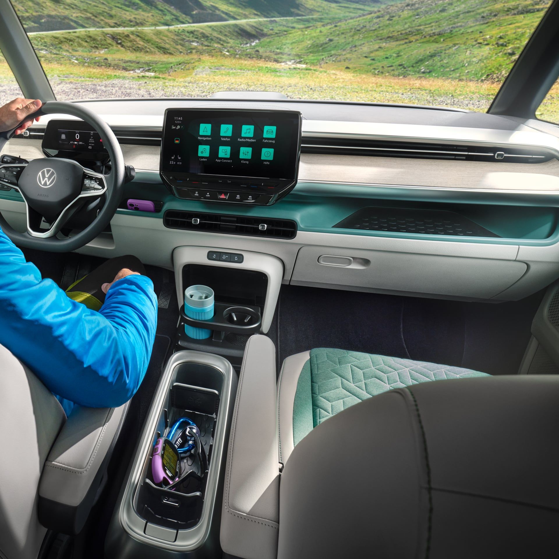 Интериор на Volkswagen ID. Buzz с водач и дигитален кокпит, подлакътник с поставка за вещи и изглед към планински пейзаж