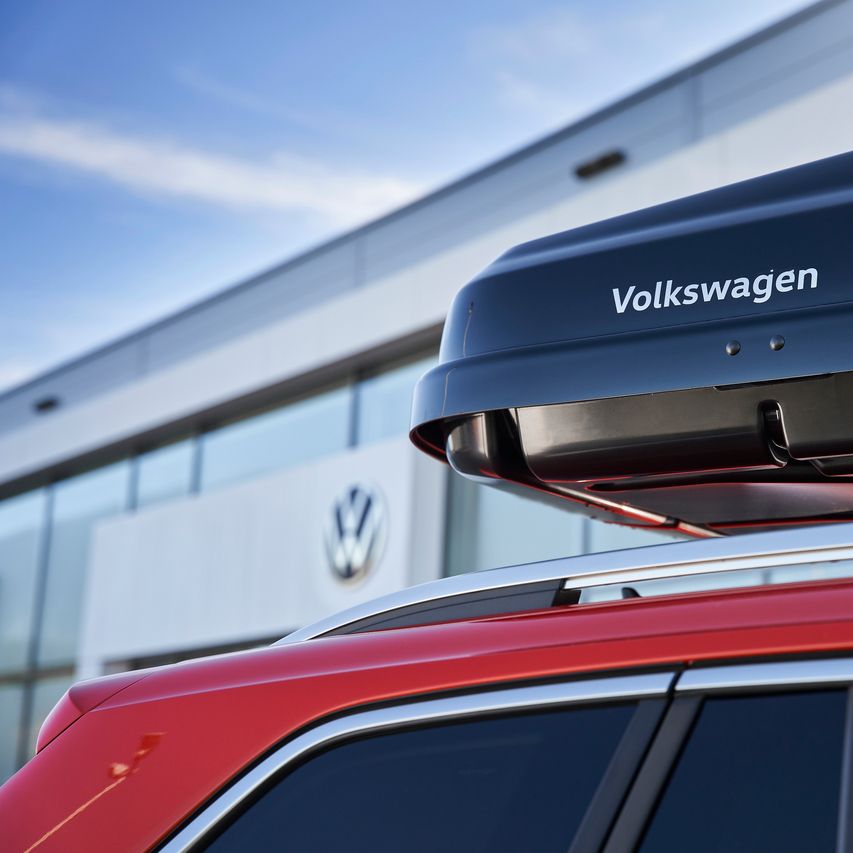 Eine schwarze Dachbox mit Volkswagen Schriftzug am Dach eines Volkswagen