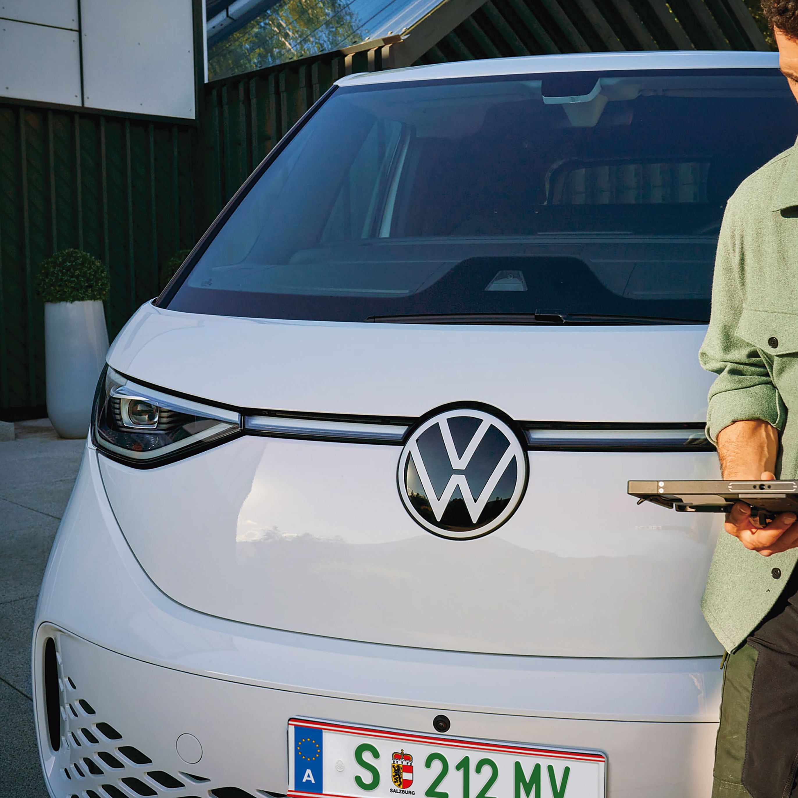 Мъж с таблет пред електрически Volkswagen ID. Buzz
