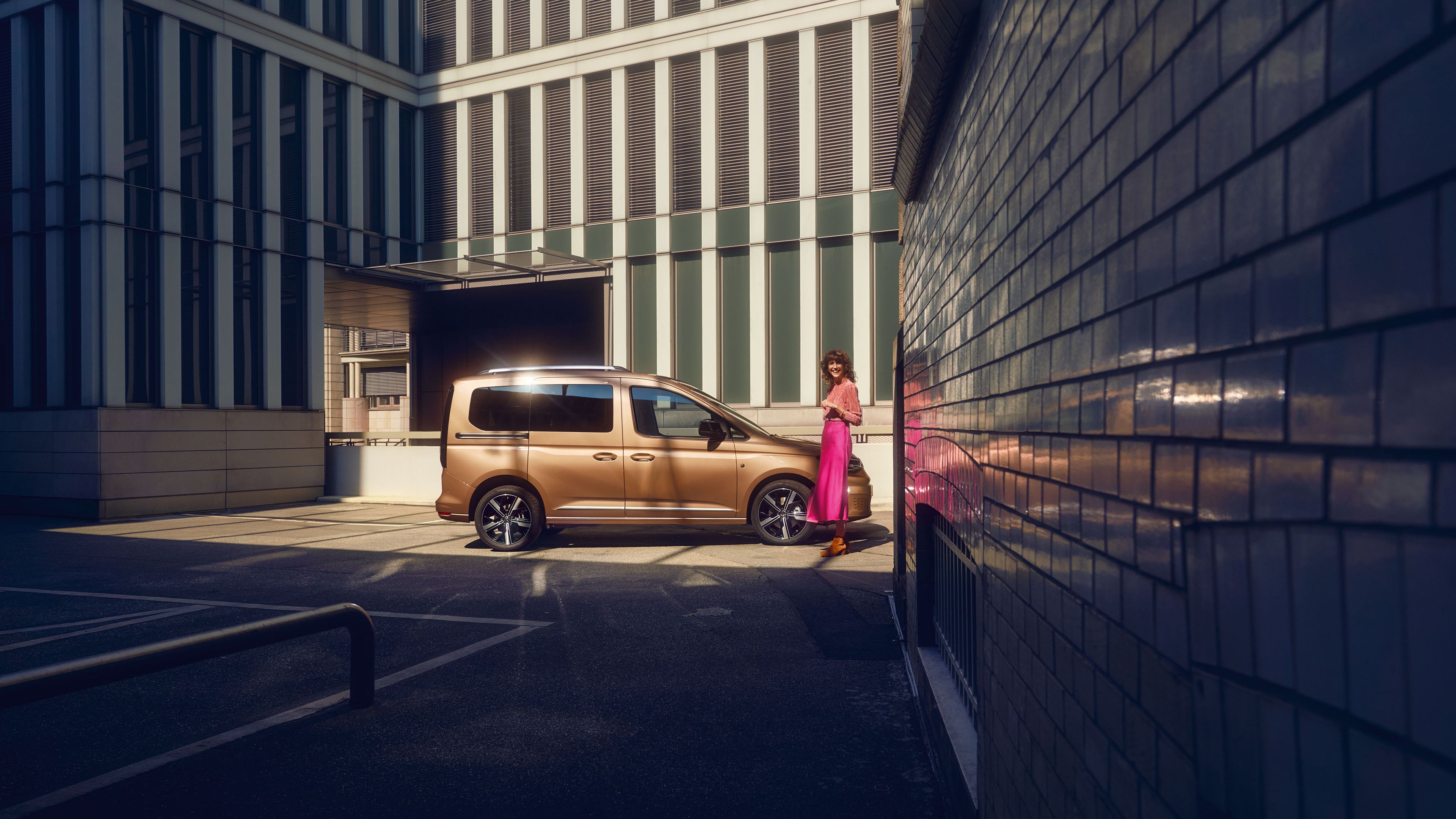Жена стои до VW Caddy, който се вижда странично.