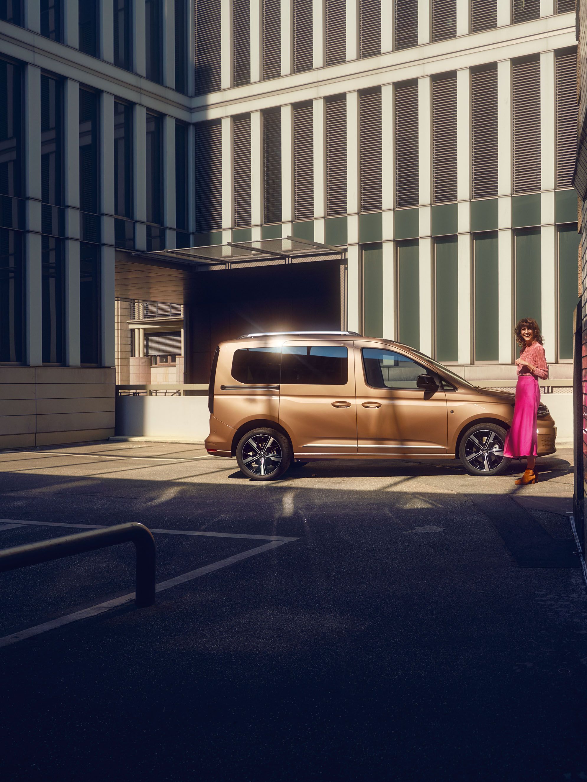 Жена стои до VW Caddy, който се вижда странично.