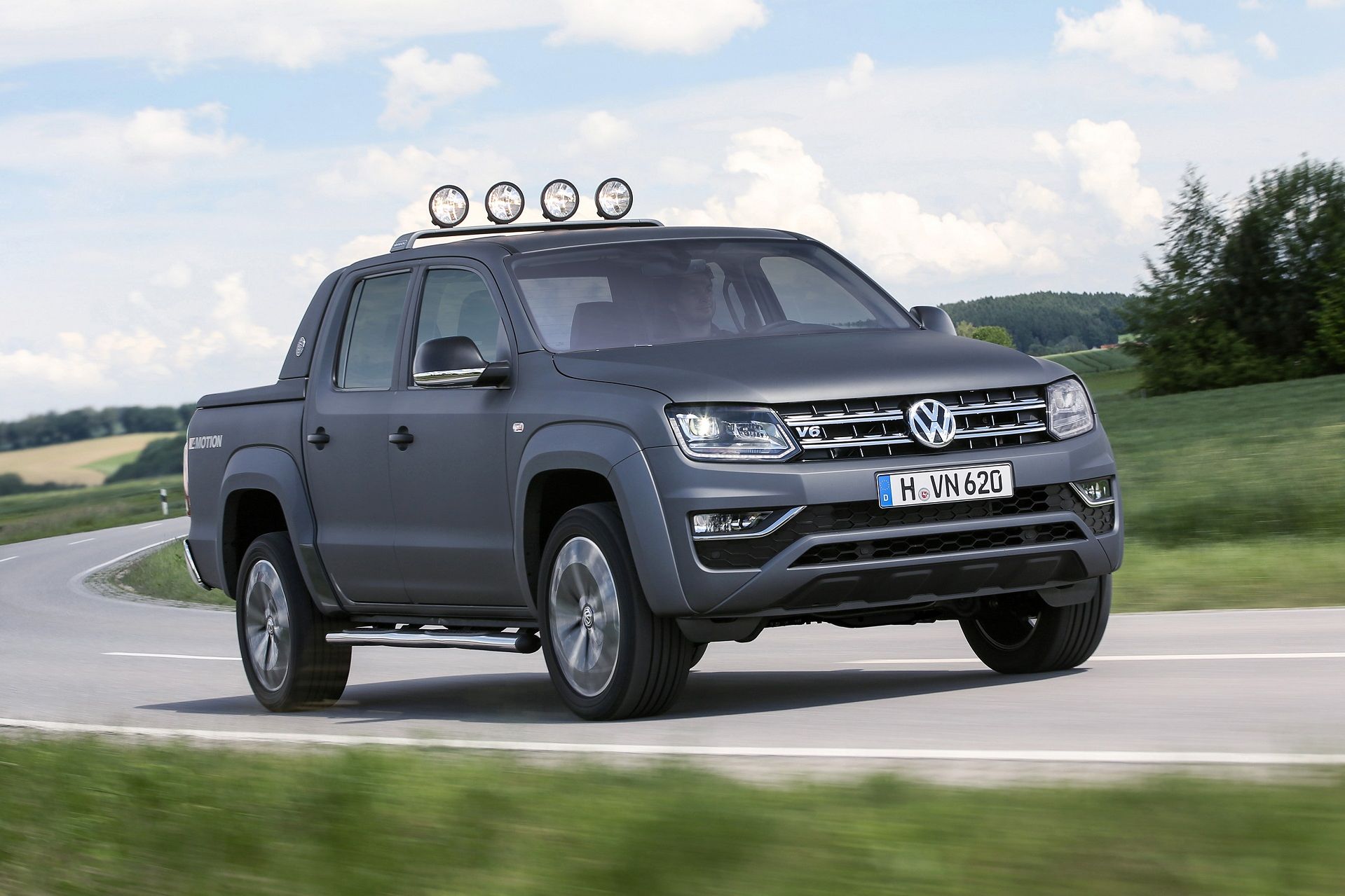 Volkswagen Amarok V6 – Сила и стил на всякакъв терен Сив Volkswagen Amarok V6 с допълнителни фарове на покрива се движи по извънградски път