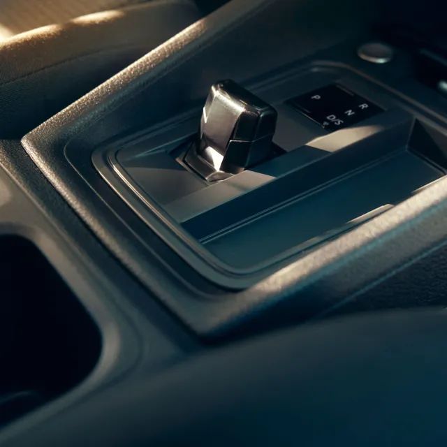 Крупен план на скоростен лост на автомобил в неутрално положение, заобиколен от съвременен интериор и бутони за управление.