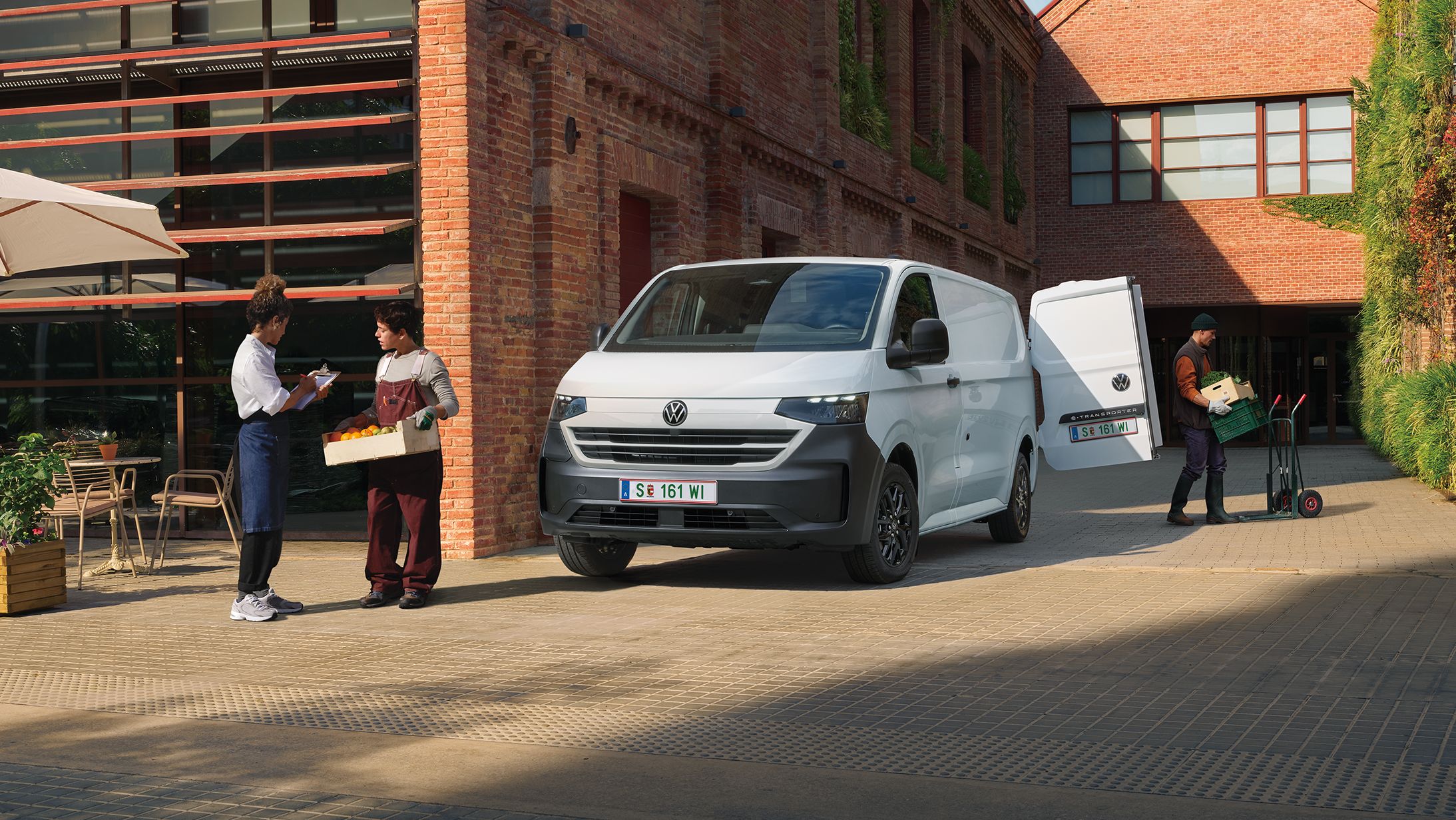 Volkswagen Transporter доставя продукти пред ресторант, докато служители приемат пратката.