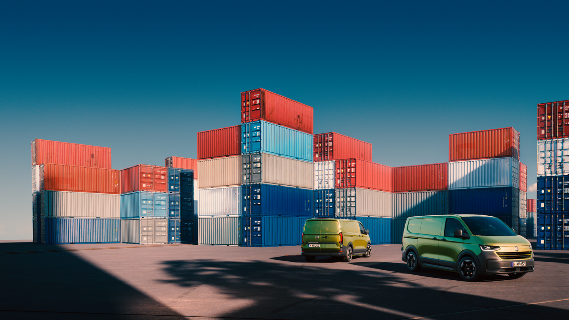Два електрически товарни микробуса Volkswagen пред редица от морски контейнери