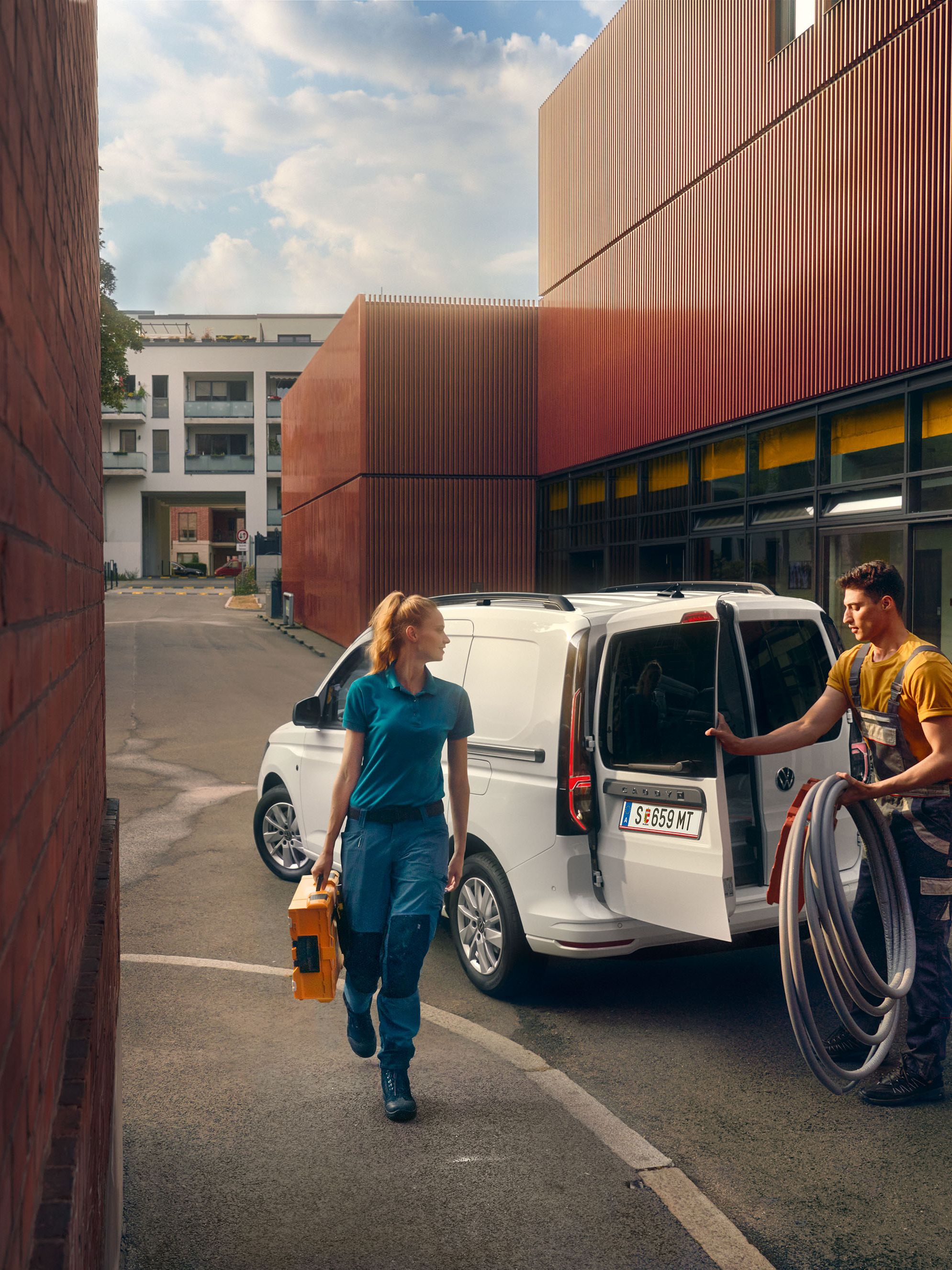 Екип от майстори разтоварва инструменти от бял Caddy Cargo