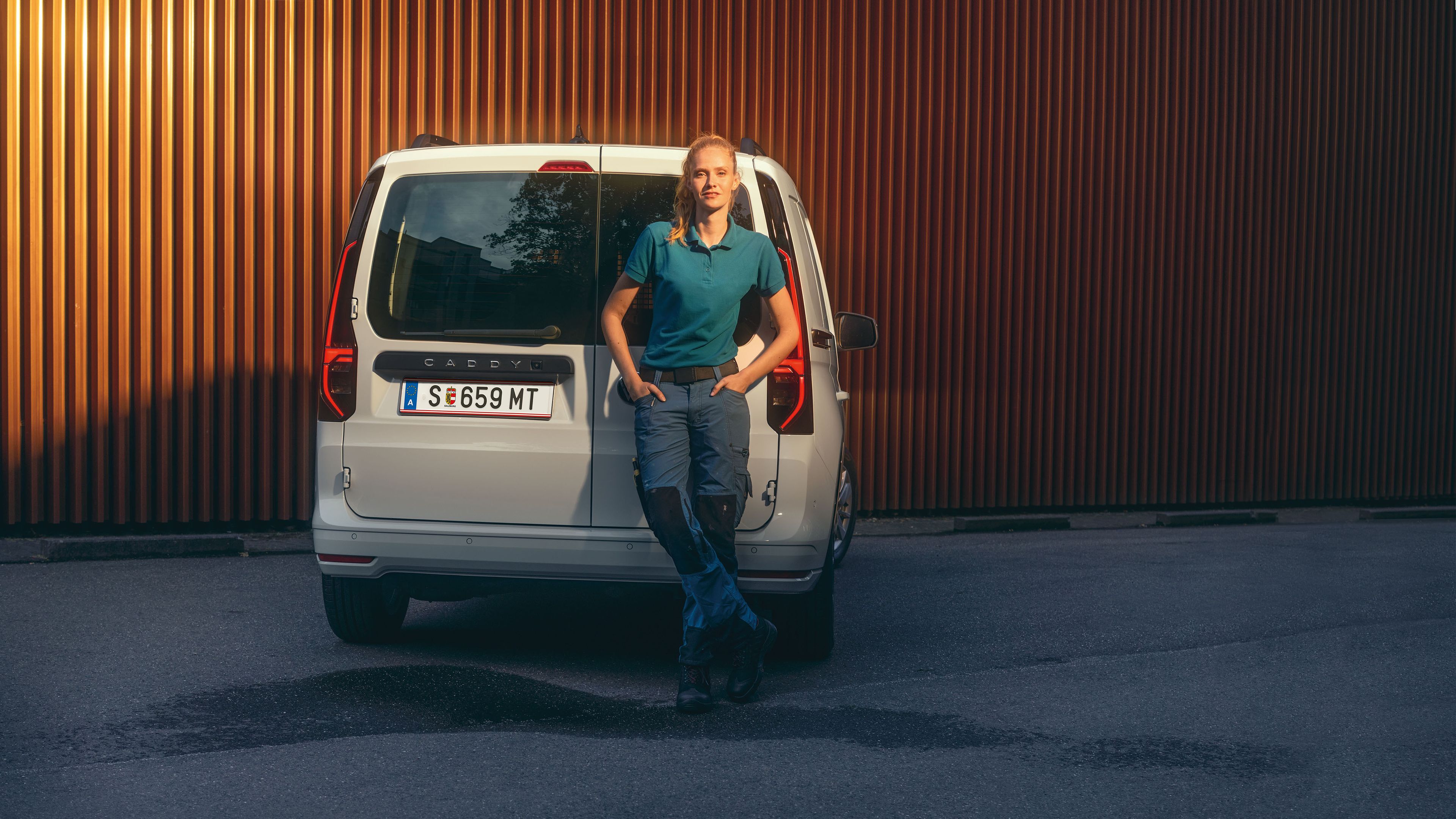 Бял VW Caddy Cargo на улицата, а пред него стои жена