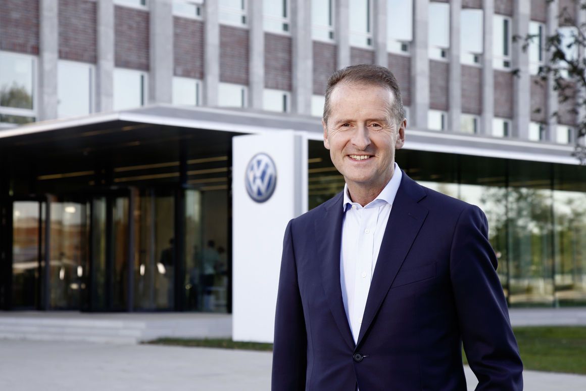 Мъж в официален костюм пред централата на Volkswagen, символизиращ управлението и бъдещата посока на компанията.