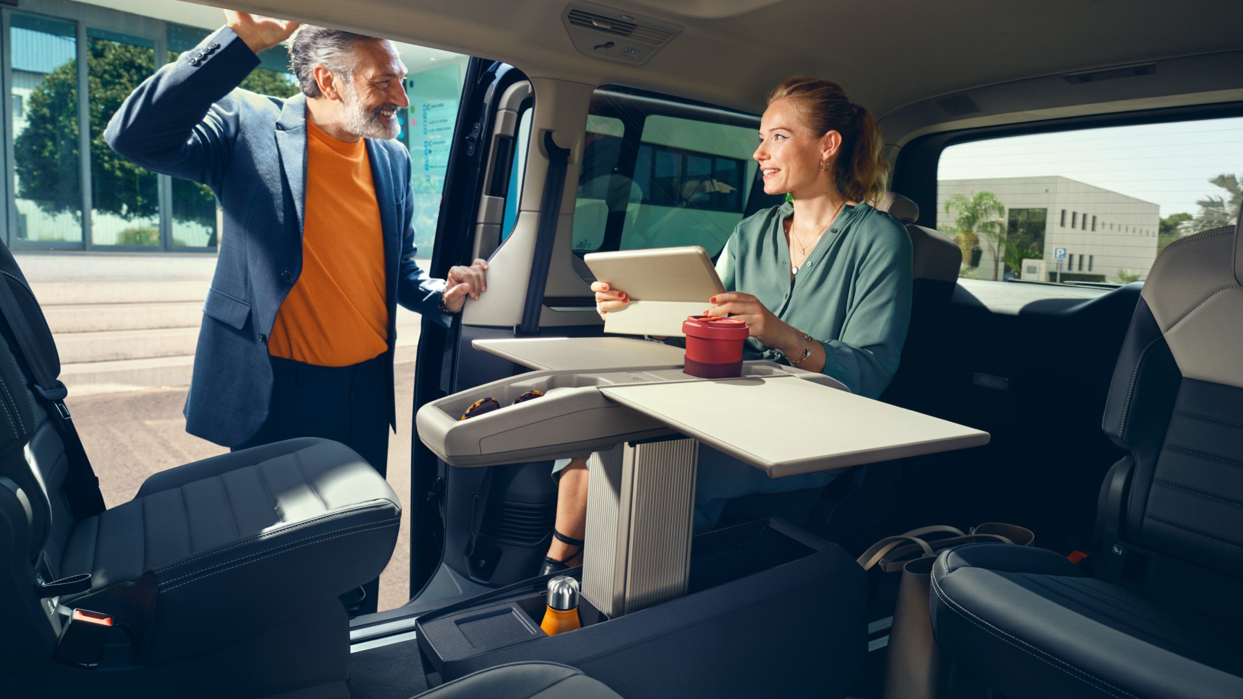 Eine Frau und ein Mann unterhalten sich am Multifunktionstisch im neuen VW Multivan T7 2021.