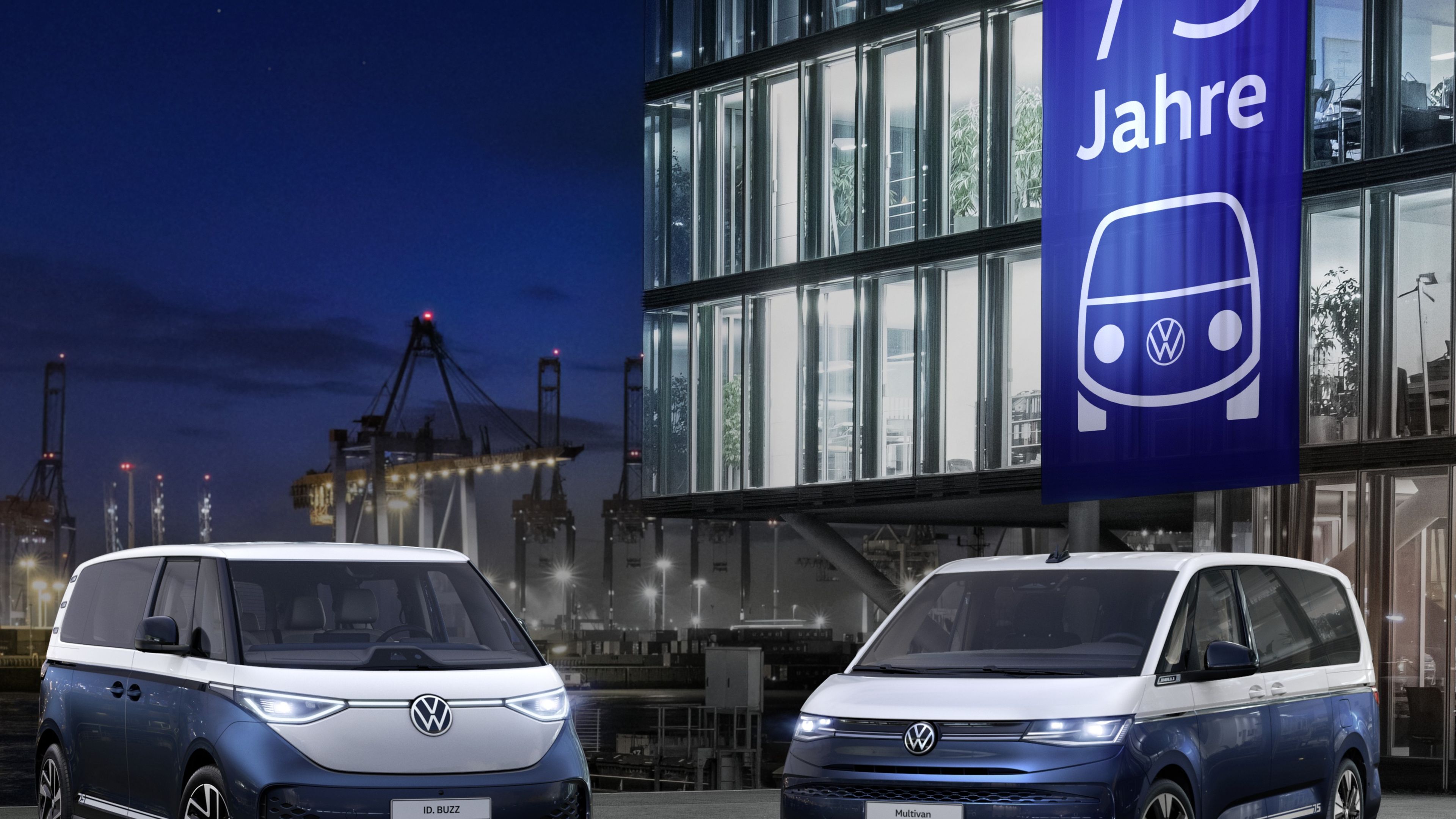 На изображението са показани два сини модела ID.Buzz и Multivan, паркирани пред модерна сграда през нощта. Сградата е осветена отвътре и отвън и има голям банер с надпис "75 Jahre", изобразяващ логото на VW. На заден план се вижда пристанище с кранове и осветени кораби.