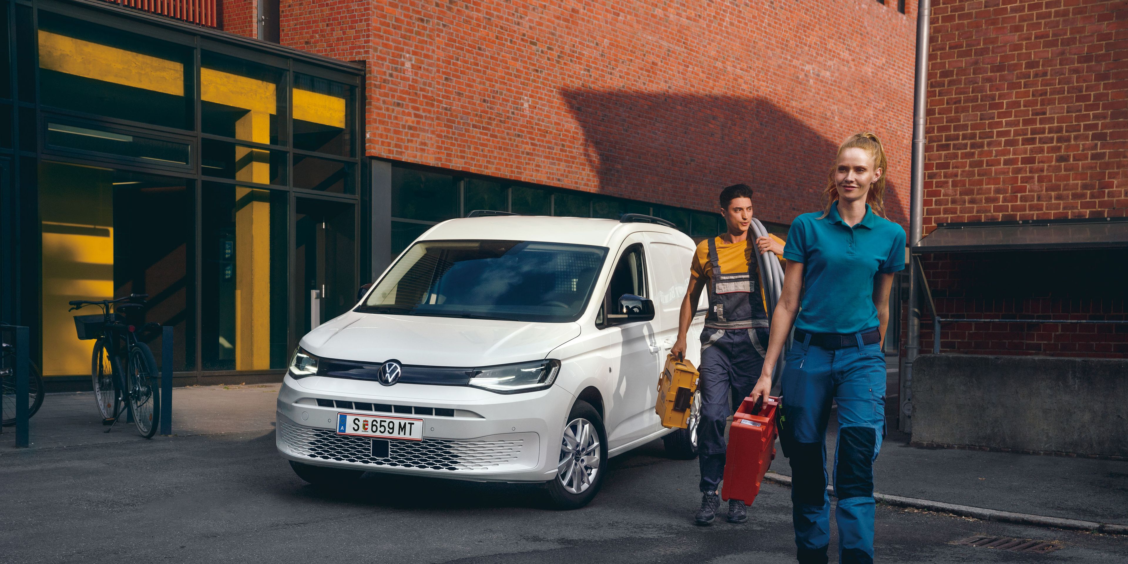 Екип от майстори пред бял VW Caddy Cargo.