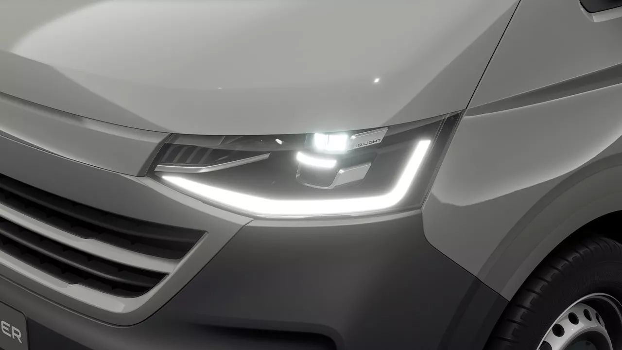 Близък план на предните LED светлини на сиво транспортно средство. Вижда се част от решетката и десния преден калник. Светлините са включени, осветявайки зоната около тях.
