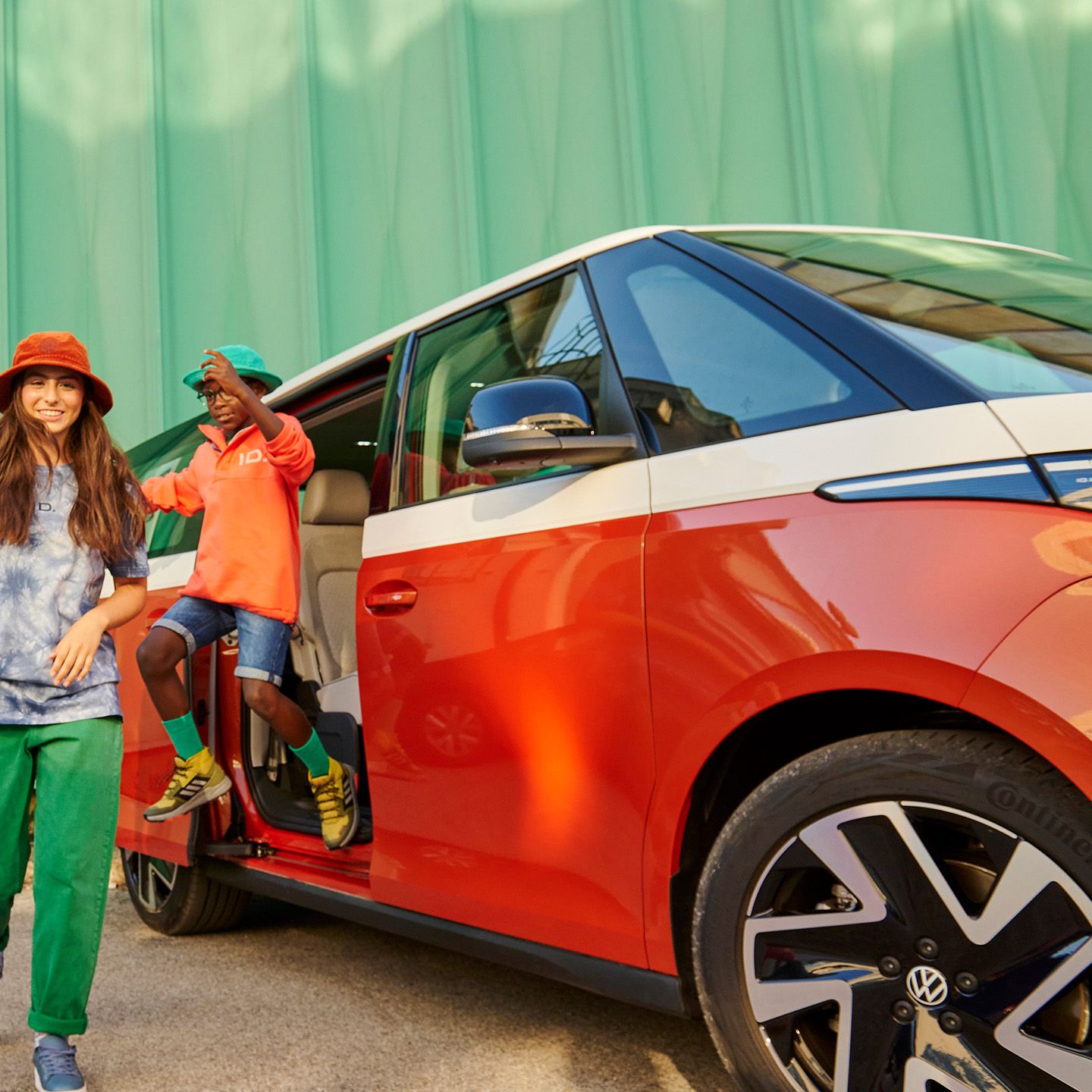 Весели моменти с Volkswagen ID. Buzz Деца с цветни дрехи и шапки играят пред Volkswagen ID. Buzz, паркиран с отворена врата