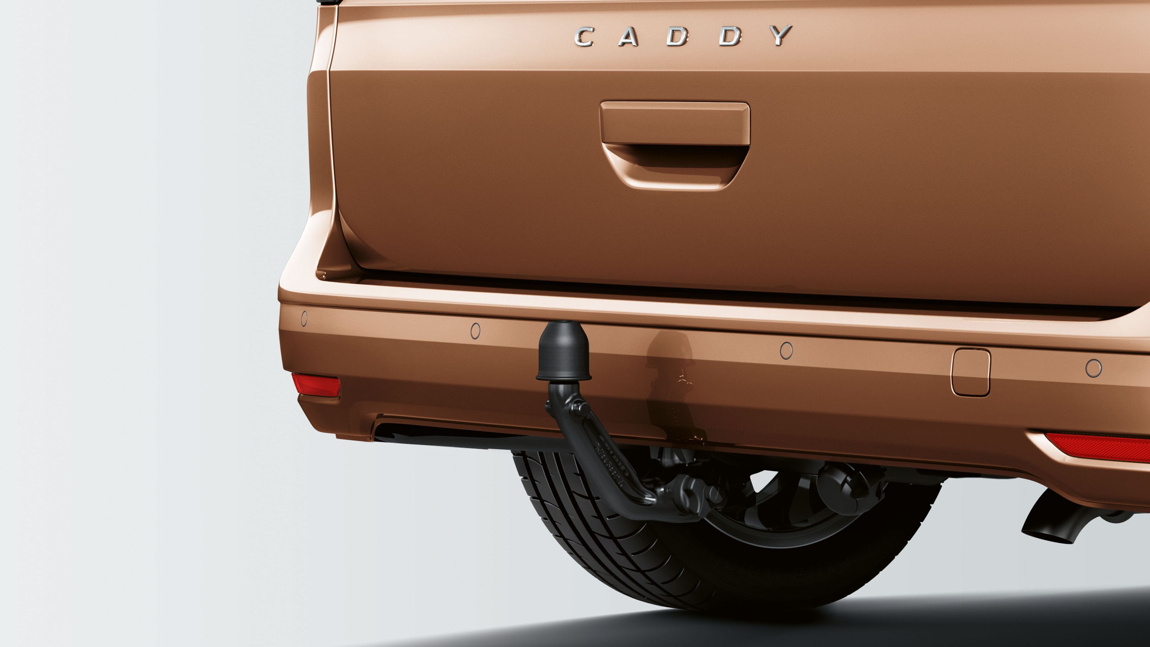 Задната част на кафяв автомобил с австрийска регистрационна табела SE 676 MI и надпис CADDY. Автомобилът е оборудван с теглич.