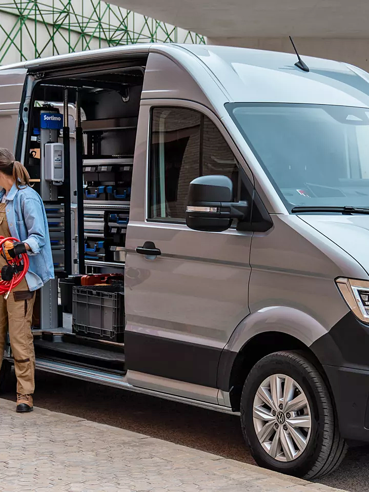 Сив Volkswagen Crafter с отворена странична врата, използван като мобилна работилница на строителен обект