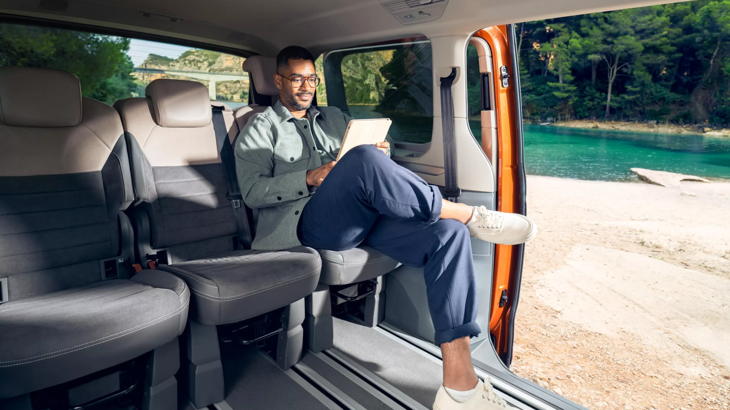 Mann sitzt auf der hintersten Sitzreihe in einem neuen VW Multivan, die Sitzreihe davor wurde ausgebaut