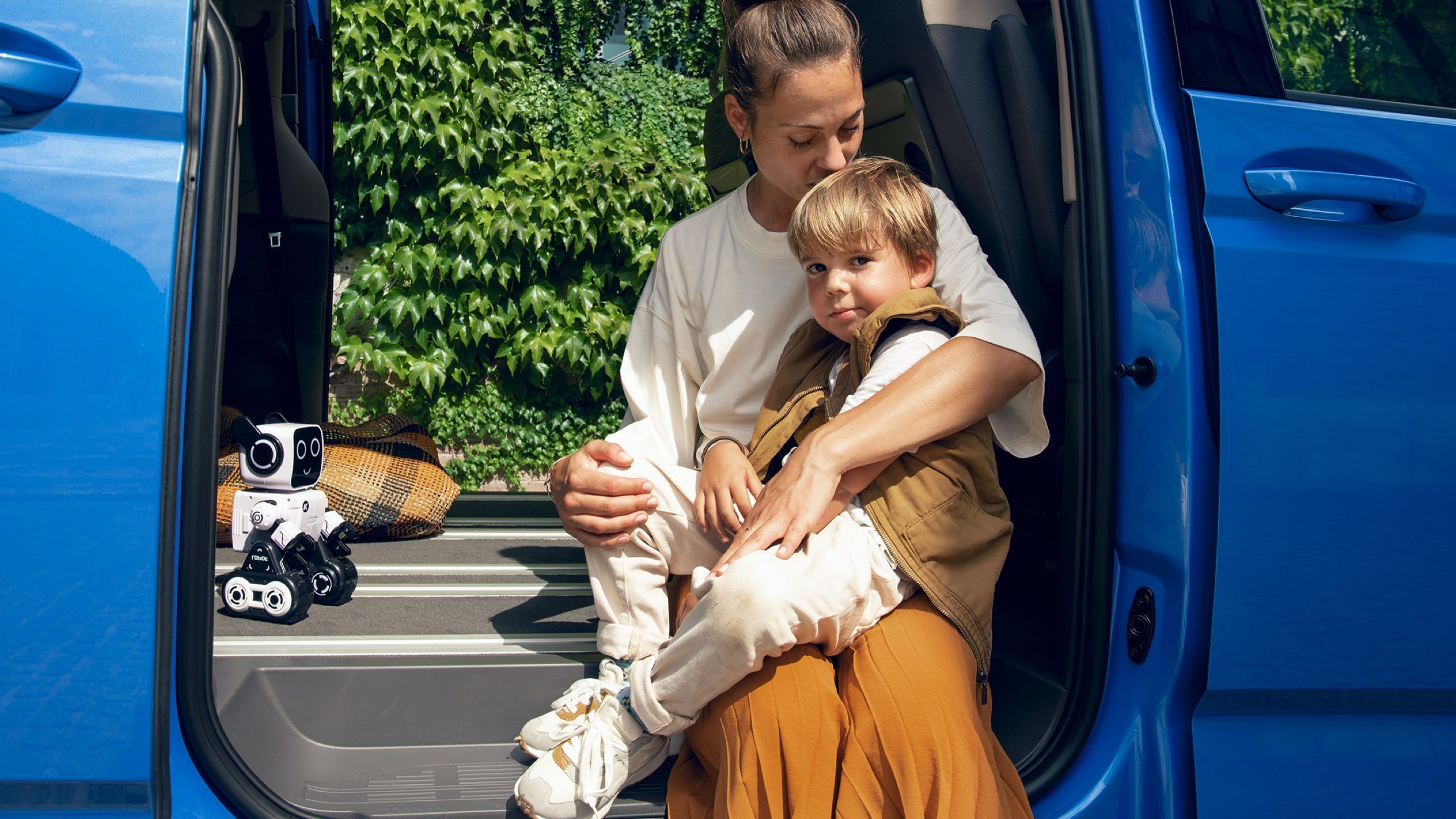 Eine Mutter sitzt mit ihrem Sohne im Rahmen der Schiebetür des VW Mutlivan T7 2021