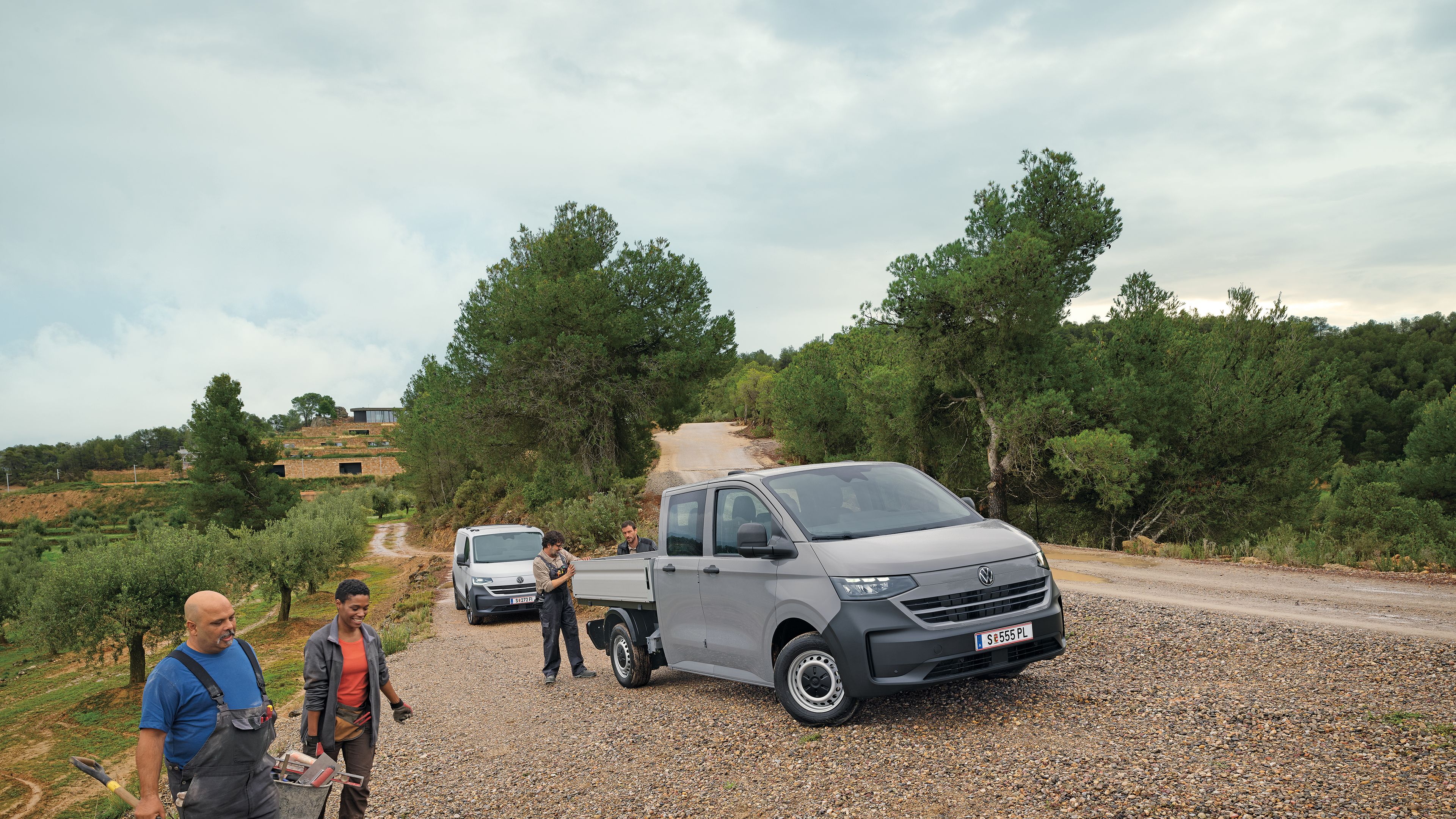 Volkswagen Transporter с двойна кабина на неасфалтиран терен с работници в работна среда