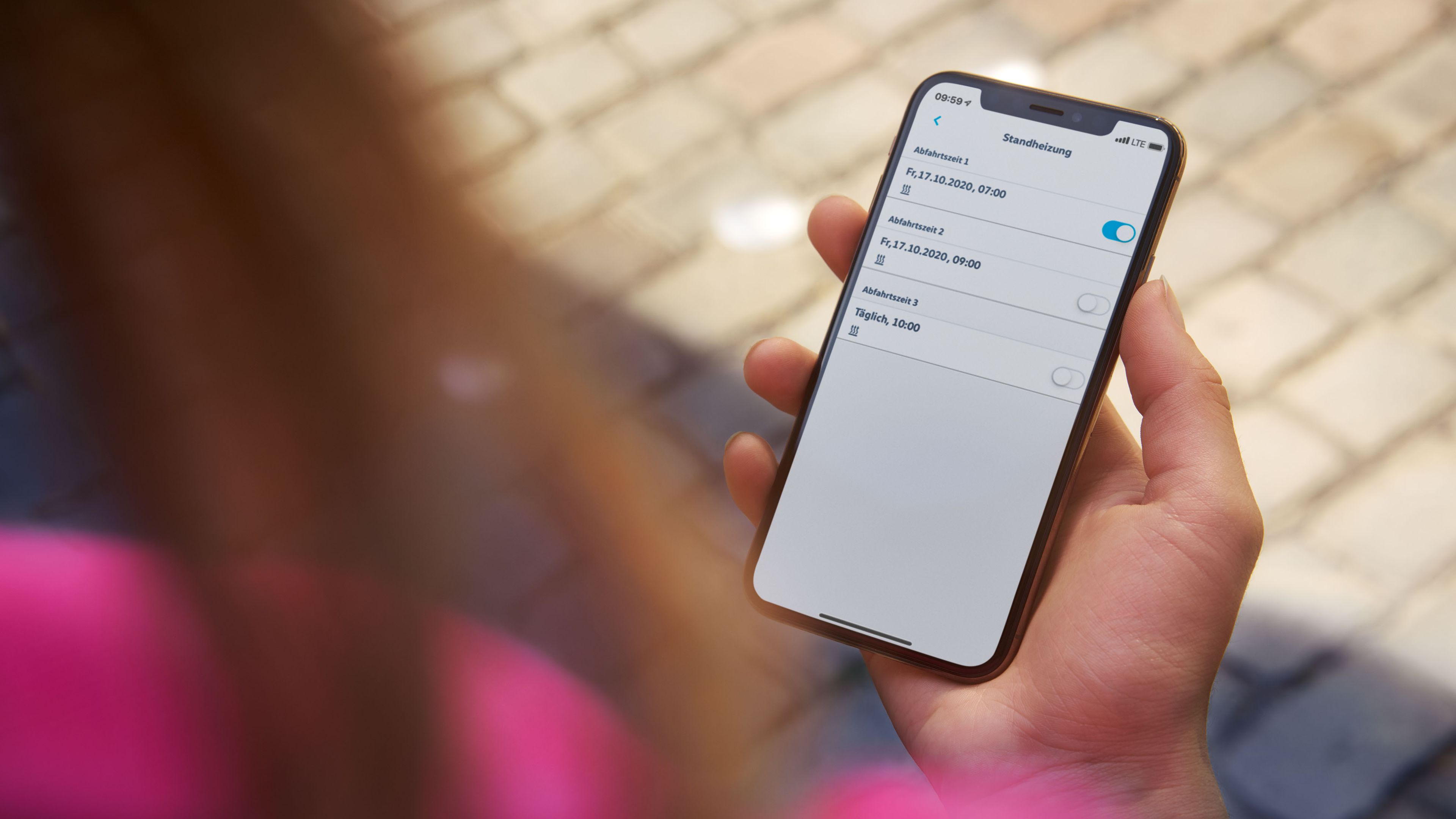 Жена държи смартфон с отворено приложение We Connect.